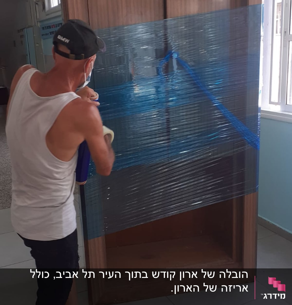 אדם עוטף ארון בעזרת ניילון נצמד כחול